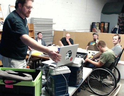 RPG Research founder running adaptive tabletop role-playing game with cerebral palsy participant at local game hobby store Merlyn's 2015.